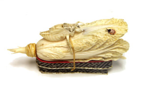 A carved and tinted ivory model of a cabbage and insects